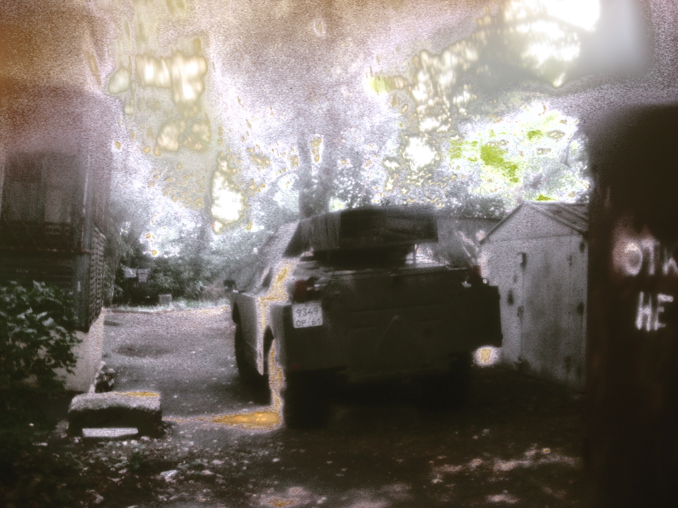 A fence and buildings marked by blur, flare and in-camera colour replacement.
