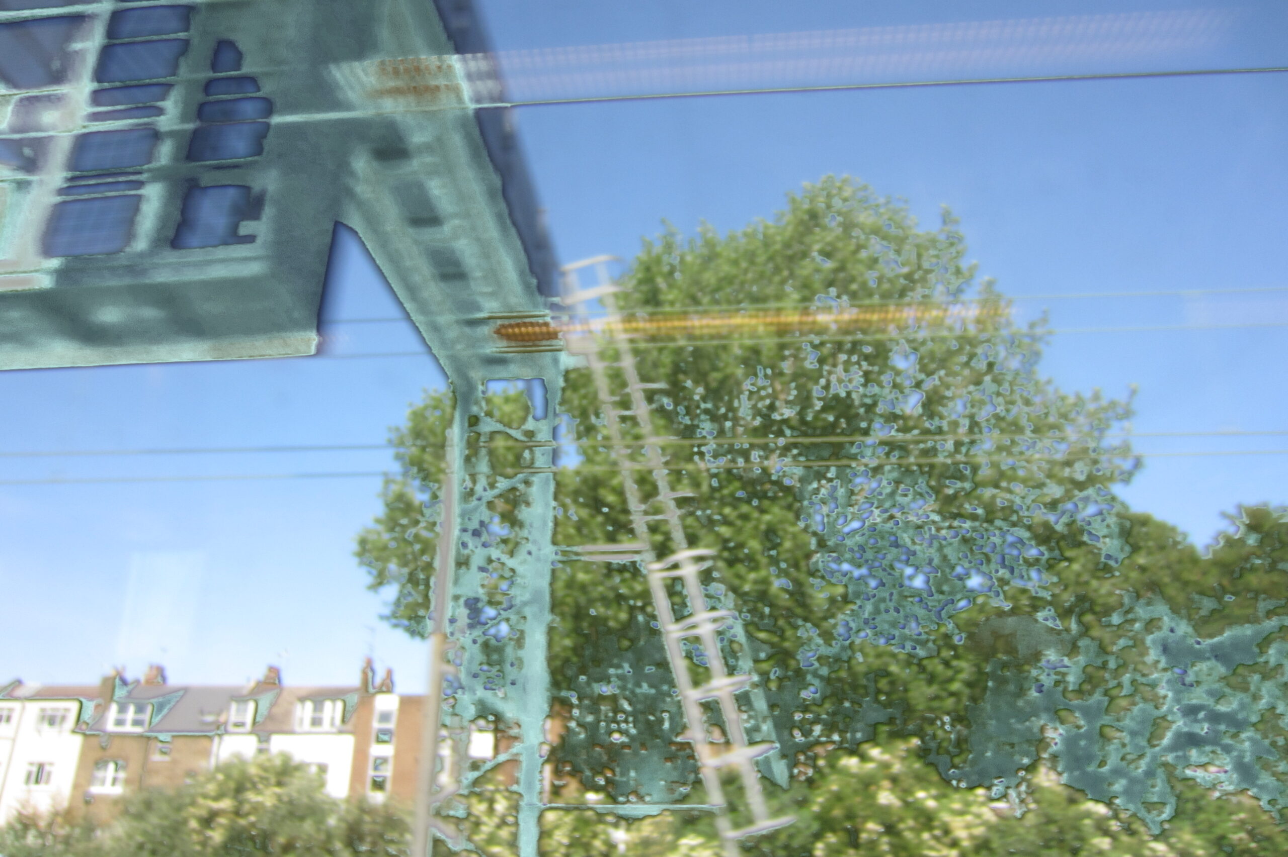 Overhead rail structure and reflected lights merging with trees and houses.