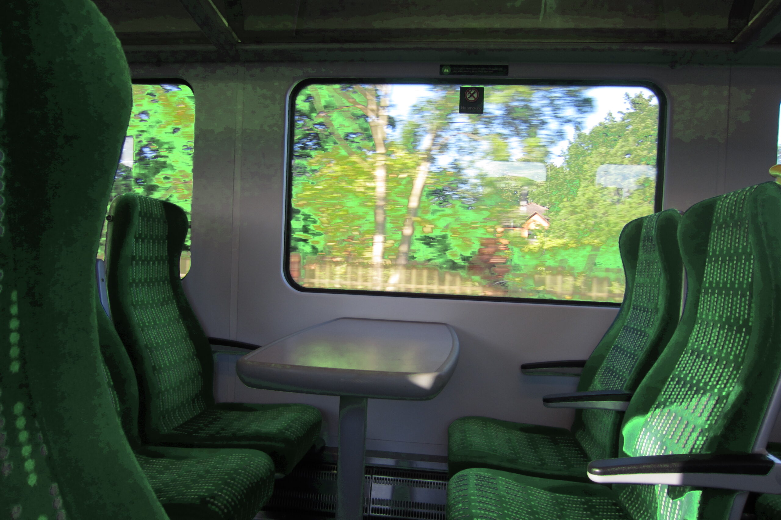 Empty green train carriage with landscape moving outside the windows.