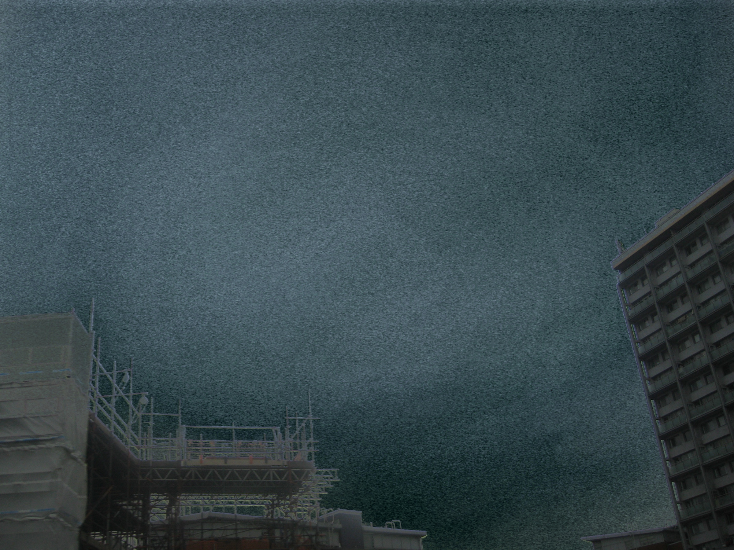 Dark grainy sky above scaffolding and buildings.