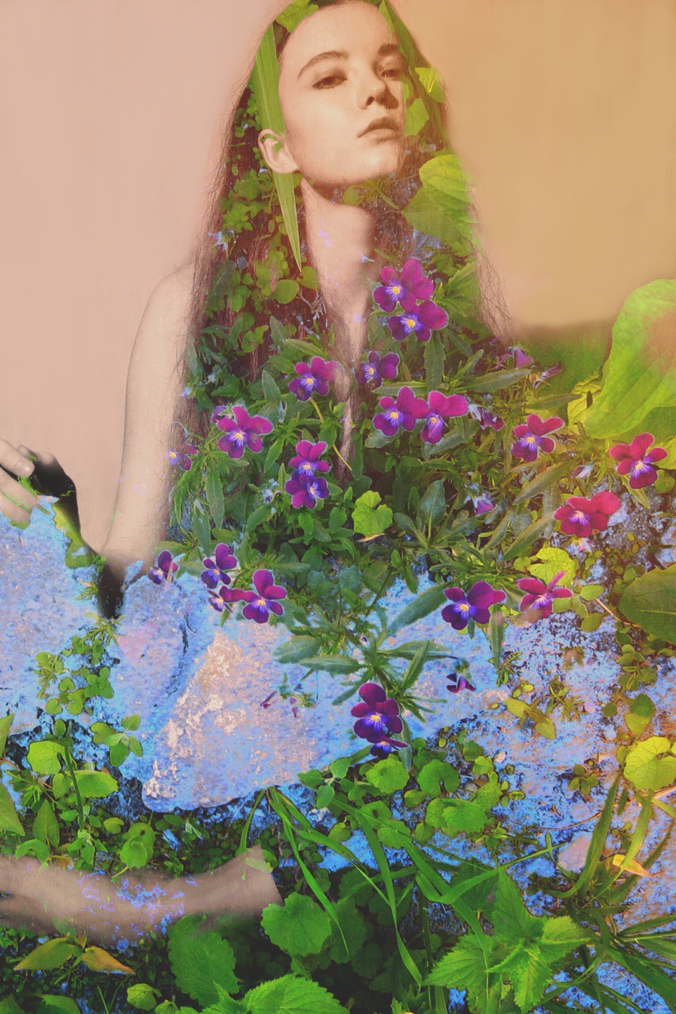 A seated figure layered with dense green foliage, small purple flowers and pale blue blossoms.