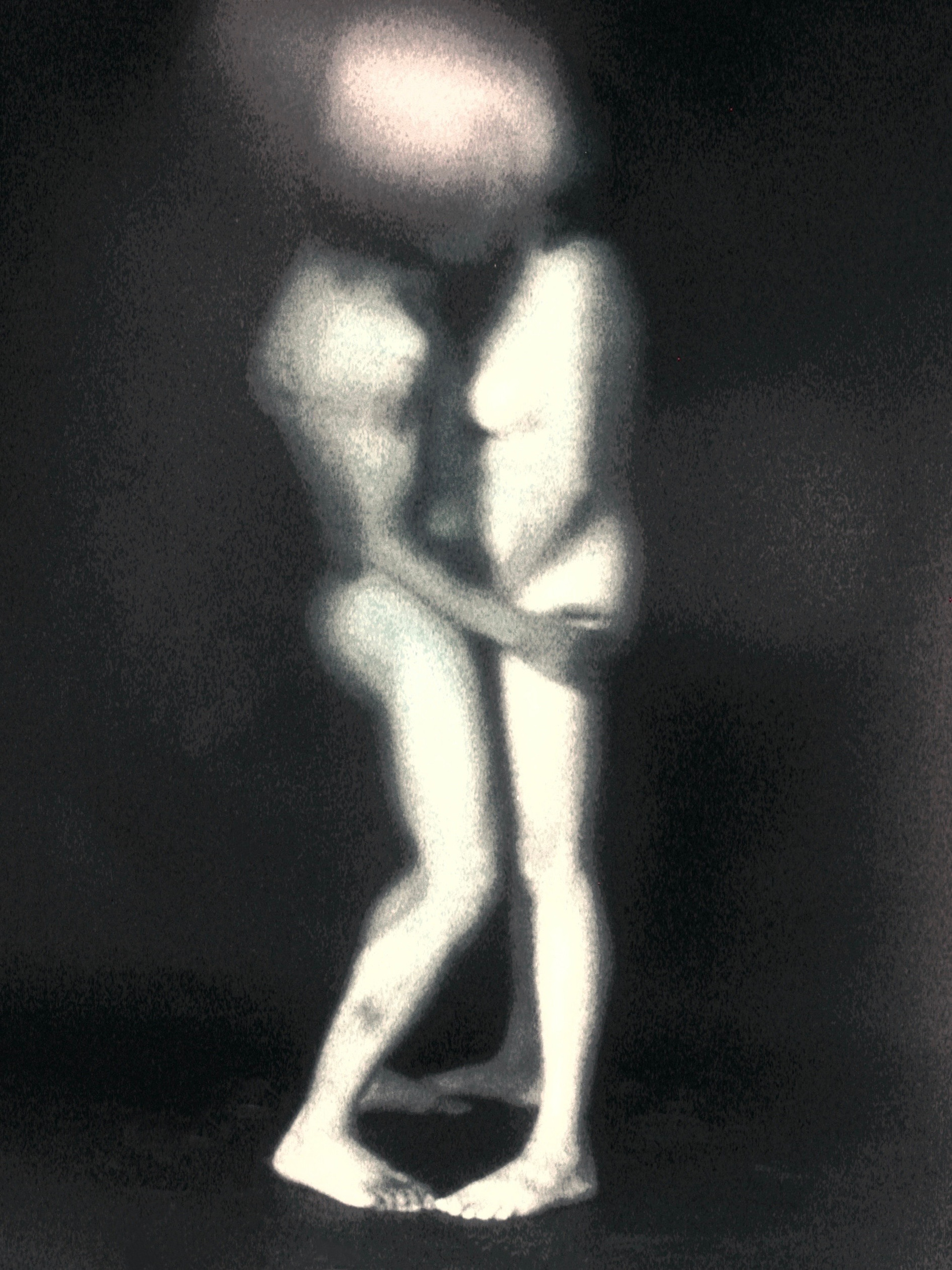 Two standing figures merge into a pale blurred form, while their legs remain distinguishable against a dark background.