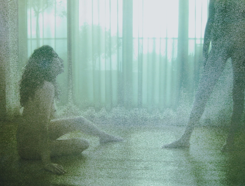 A seated figure at the left and a partially visible standing figure at the right, separated by light from a window.